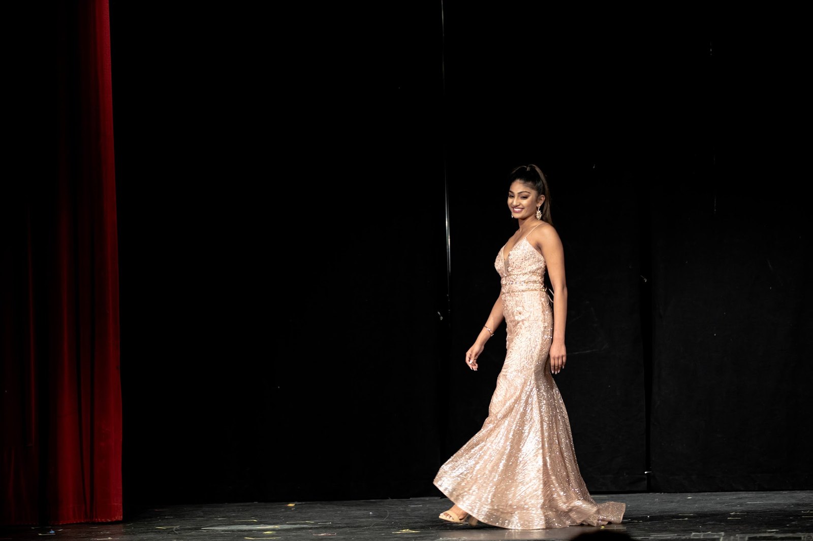 Mahika Valluri walking the stage in a rose gold sequin gown